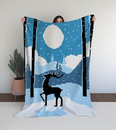 a woman is holding up a blanket with a deer in the night sky on it