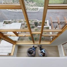 two people are sitting on bean bags in the middle of a room with large windows