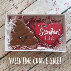 two decorated cookies in a box with valentine's day messages on them and the words you're stinkin'cute