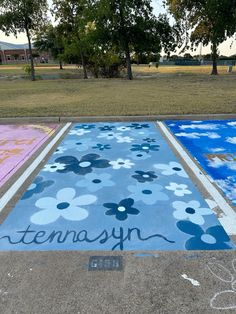 the sidewalk has been painted with blue and white flowers on it, along with words that read tenasyn