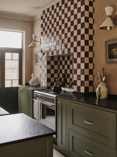 a kitchen with green cabinets and checkered backsplash on the wall above the stove