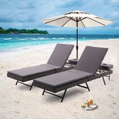 two lounge chairs and an umbrella sit on the sand at the beach, with drinks in front of them