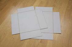 four pieces of white paper sitting on top of a wooden floor