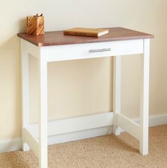 a small white desk with a book on top