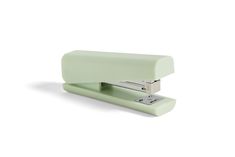 a green stapler sitting on top of a white surface