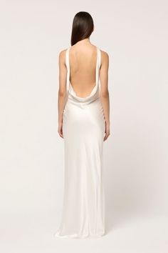 the back of a woman wearing a long white dress with an open back and straps