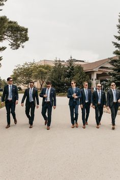 a group of men in suits and ties walking down a street together with sunglasses on