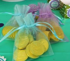 two bags filled with gold coins sitting on top of a green tablecloth covered table