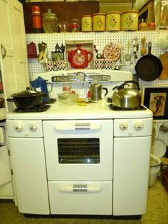 an old fashioned white stove with pots and pans on it