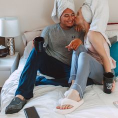 a man and woman sitting on top of a bed with their feet in the air