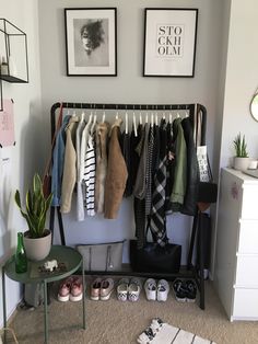 an organized closet with clothes and shoes hanging on the rack next to a small table