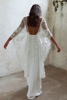 the back of a woman wearing a white wedding dress with sheer sleeves and an open back