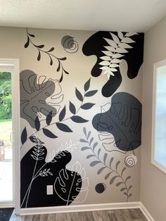 the wall is painted with black and white flowers, leaves, and plants on it