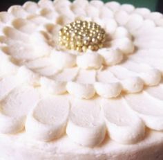 a close up view of a cake with white frosting and gold decorations on top