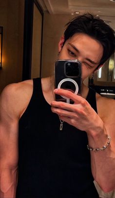 a man taking a selfie with his cell phone in front of him and wearing a black tank top