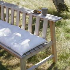 a wooden bench sitting in the grass next to a bowl of fruit on top of it