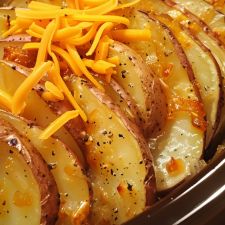 sliced potatoes with cheese and seasoning in a slow cooker