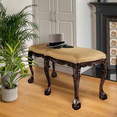 a wooden bench sitting next to a potted plant on top of a hard wood floor