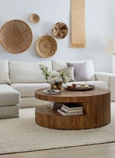 a living room with white couches and round coffee table in the center, surrounded by woven wall hangings