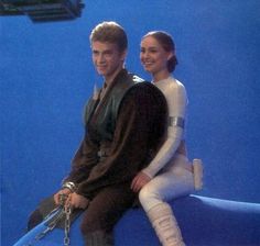 a man and woman sitting on top of a blue object