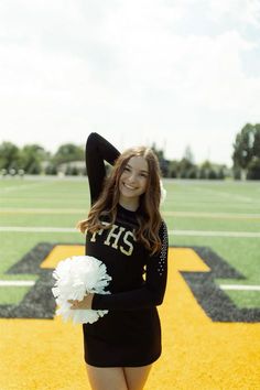 a young woman in a cheerleader outfit poses on the football field