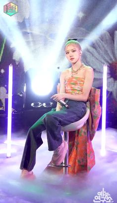 a woman sitting on top of a chair in front of a stage with lights behind her