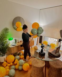 a woman is holding balloons in the middle of a room filled with oranges and other decorations