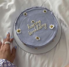 a woman is decorating a birthday cake with daisies and the words happy birthday on it