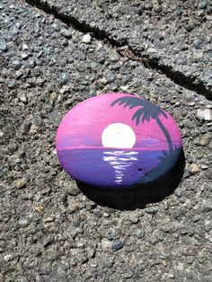 a painted rock with a palm tree on it sitting in the middle of a road