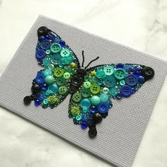 a butterfly made out of buttons sitting on top of a piece of paper