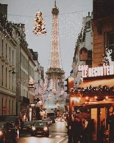 the eiffel tower is lit up with christmas lights and people walking down the street