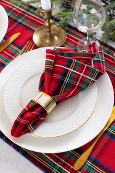 the table is set with red and green plaid napkins, gold trimmed placemats, and silverware