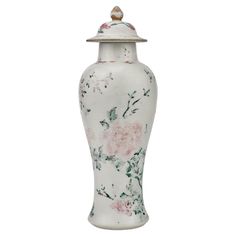 a white vase with pink flowers and a bird sitting on the top of it's lid