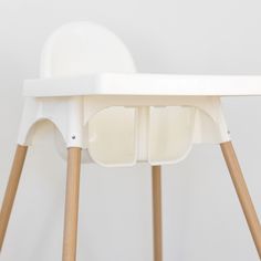 a white high chair with two wooden legs