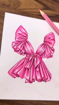 a drawing of a pink bow on top of a piece of paper with colored pencils next to it