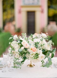 a white table topped with flowers and greenery