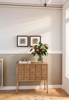 a vase with flowers sitting on top of a wooden dresser