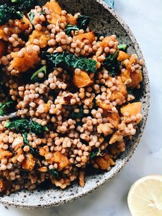 a bowl filled with lentils and spinach on top of a white marble table