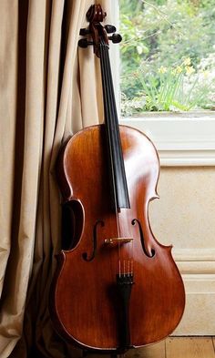 an old cello leaning against a window sill