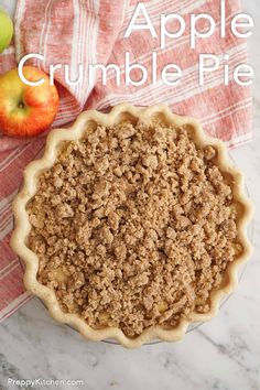 an apple crumble pie sitting on top of a table next to an apple slice