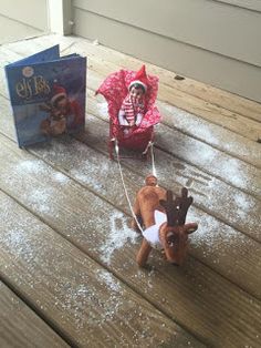 a small child riding on a sled pulled by a reindeer with an elf hat