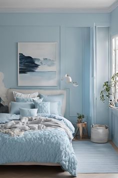 a bedroom with blue walls and bedding in the corner, along with a painting on the wall