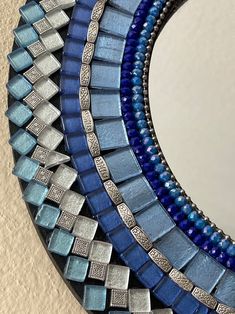 three blue and silver mosaic tiles are arranged in the shape of a circle on a wall