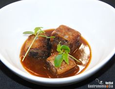 some food is in a white bowl on a black tablecloth and there are green garnishes