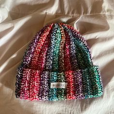 a multicolored knit beanie sitting on top of a bed