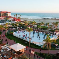 an aerial view of people skating on the ice rink near the beach in front of a hotel