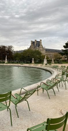 green lawn chairs sitting in front of a fountain