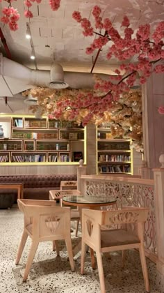 the interior of a restaurant with cherry blossom hanging from the ceiling and wooden tables, chairs, and bookshelves