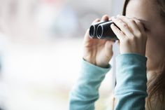 a woman is looking through a binoculars lens