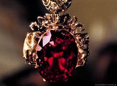 a large red stone sitting on top of a gold chain